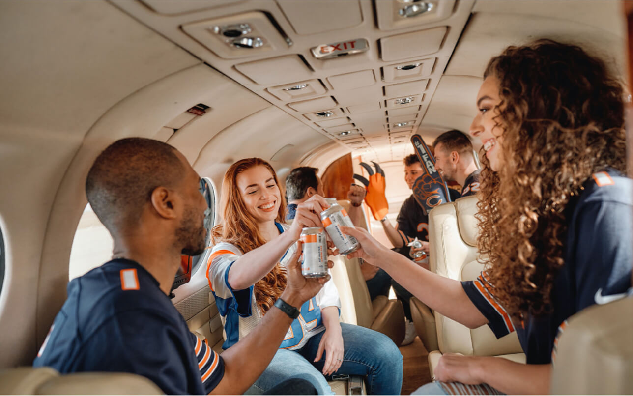 group of friends in chicago bears gear toasting beers on personal charter flight